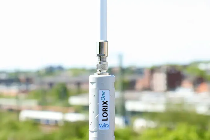 Nahaufnahme einer weißen Antenne mit der Aufschrift LORIX One, eine unscharfe Stadtlandschaft im Hintergrund.