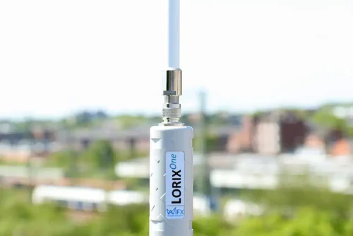 Nahaufnahme einer weißen Antenne mit der Aufschrift LORIX One, eine unscharfe Stadtlandschaft im Hintergrund.