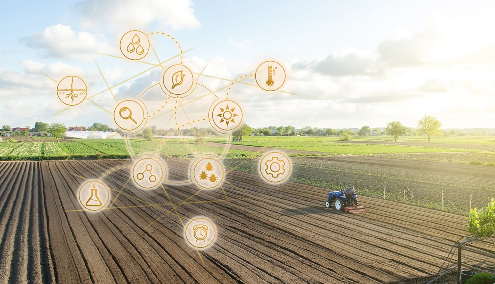 A farmer on a blue tractor tills a vast, sunlit field. Overlaid icons represent agriculture technology, including water, temperature, and growth symbols.