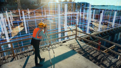 Ein Bauingenieur mit Vermessungsgerät auf Baustelle, umgeben von einer holografischen Darstellung von Gebäudestrukturen.