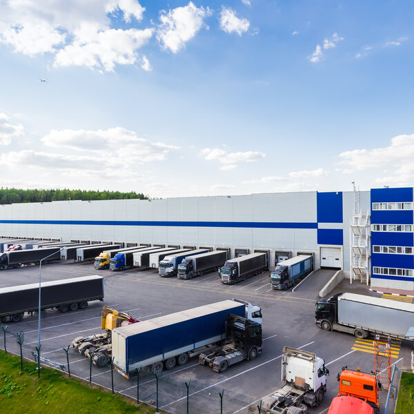 Ein Großes Logistikzentrum mit vielen Lastwagen, die an Laderampen be- und entladen werden.