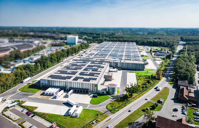 Eine Luftbildaufnahme von einem großen Logistikzentrum, auf dessen Dach zahlreiche Solaranlagen installiert sind.