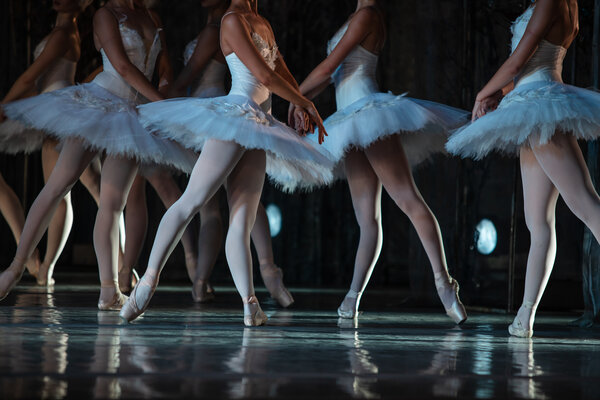 Mehrere Ballerinen in weißen Tütüs und Spitzenschuhen tanzen auf der Bühne.