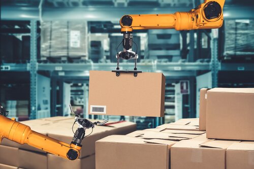 Zwei gelbe Roboterarme heben und bewegen einen Karton mit Barcode in einem Lager voller gestapelter Kisten.