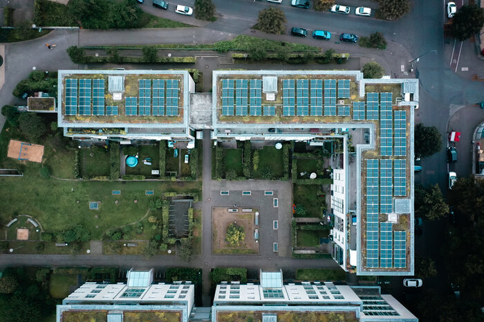 Eine Wohnanlage mit begrünten Dächern und großen Solaranlagen aus der Vogelperspektive, mit von Innenhöfen und Grünflächen.