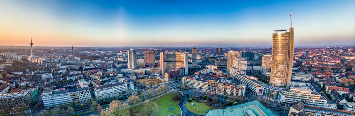 Ein Panoramablick auf die Stadt Essen, der auch hohe Gebäude, einen Park und den Horizont zeigt.