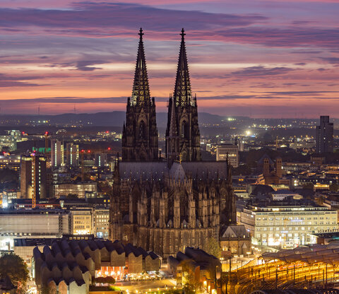 Ein Panoramablick auf den auf die Stadt Köln mit dem Kölner Dom im Mittelpunkt bei Abenddämmerung.