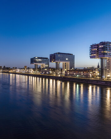 Kranhäuser im Kölner Rheinauhafen am Rhein bei Abenddämmerung.