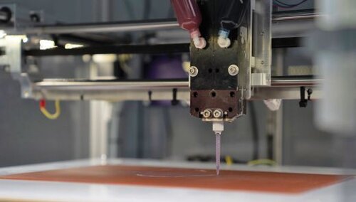 Eine Nahaufnahme eines 3D-Druckers, der Material auf eine Plattform aufträgt.