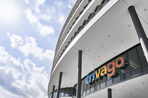 Außenansicht eines modernen Bürogebäudes mit dem großen Logo trivago an der Glasfassade.