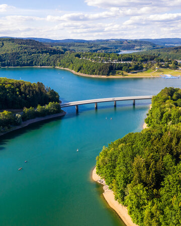 Luftaufnahme des Biggesees mit Uferlandschaft und Brücke in Südwestfalen.
