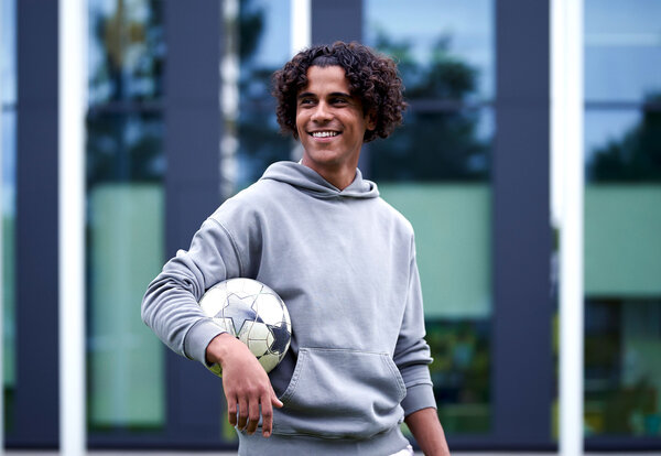 Ein Mann mit Fußball unter dem Arm schaut in die Ferne.