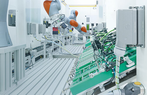 Roboterarme in einer modernen Fertigungsanlage montieren Bauteile an einer automatisierten Produktionslinie.