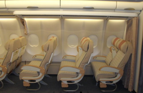 Row of four airplane seats with beige cushioning and brown accents, positioned next to large oval windows, conveying a calm and orderly atmosphere.