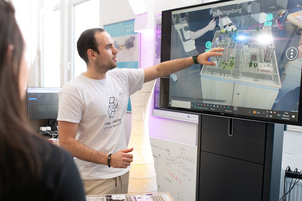 A man presents an augmented reality environment on a screen, with a digital city model at its centre.